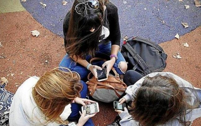 Tres jóvenes revisan sus móviles.