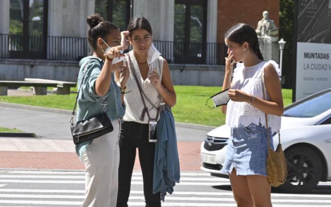Tres jóvenes sin mascarilla pasean por una calle Tres jóvenes sin mascarilla pasean por una calle
