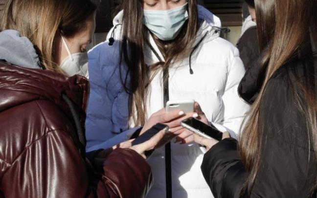 Tres jóvenes consultan sus móviles en Vitoria.