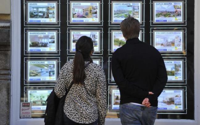 Jóvenes observan pisos en una inmobiliaria.