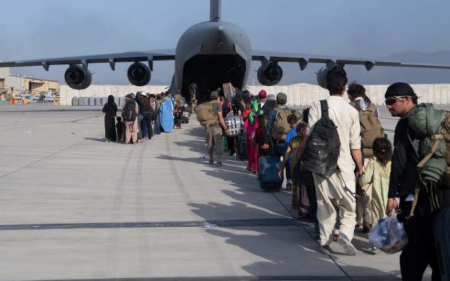 Afganos hacen cola para embarcar en un avión en Kabul. Afganos hacen cola para embarcar en un avión en Kabul.