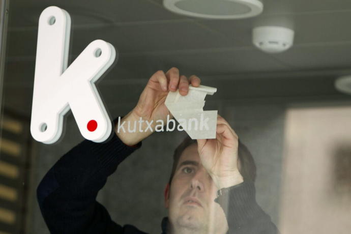 Trabajador colocando el rótulo con el logotipo de Kutxabank en una sucursal