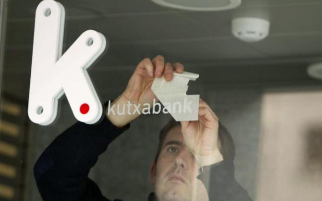Trabajador colocando el rótulo con el logotipo de Kutxabank en una sucursal