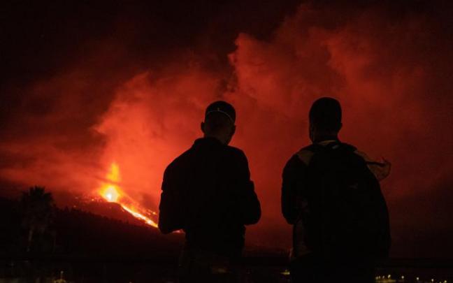 Dos jóvenes observan esta madrugada la erupción del volcán de La Palma.