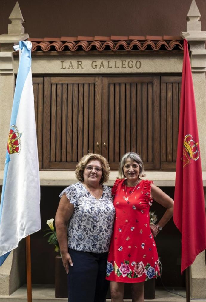 La presidenta y la vocal de cultura del Lar Gallego posan frente al horreo de la institución