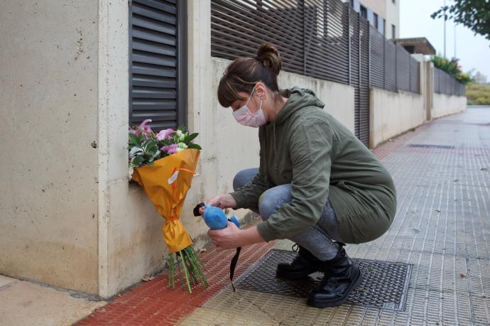 Una mujer coloca flores en el portal en el que fue hallado el niño