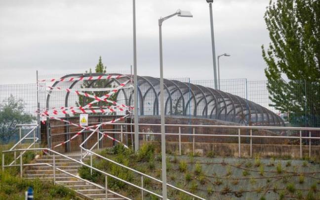 Las vallas y cintas impiden el paso de los peatones por la pasarela desde hace un año.