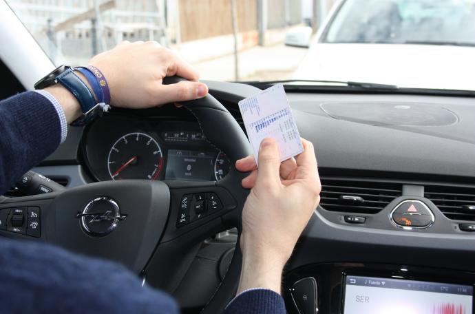 Un hombre muestra su permiso de conducción.