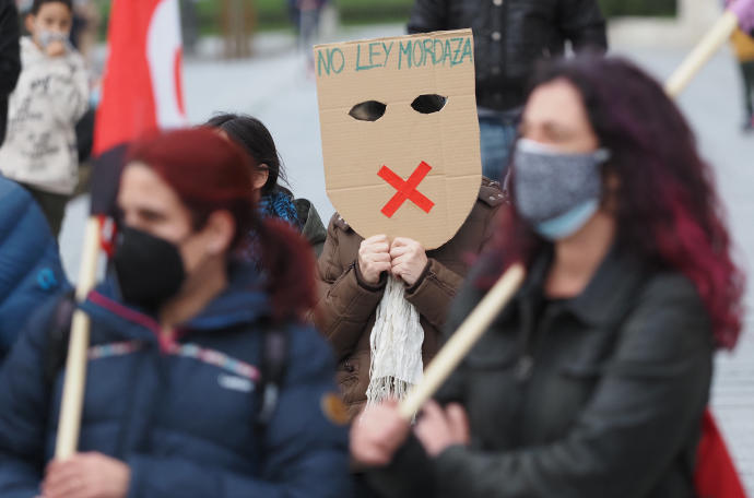 Una persona sostiene una careta donde se lee "No Ley Mordaza" durante una manifestación.