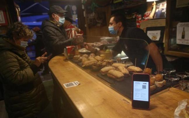 Un camarero vizcaino revisa el pasaporte covid de varios clientes. Foto: Borja Guerrero