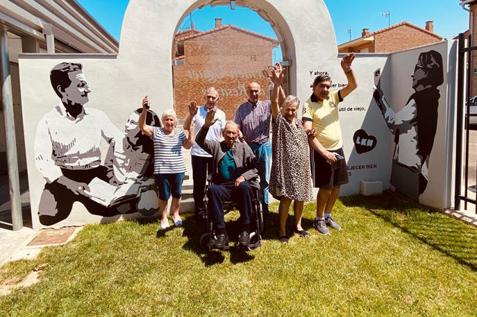 Personas mayores usuarias del centro de día El Pórtico de Ablitas, con el mural de LKN.