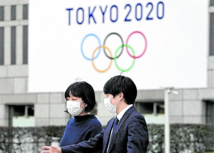 Dos personas pasan por delante de un logo de los Juegos Olímpicos de Tokio. Foto: Efe