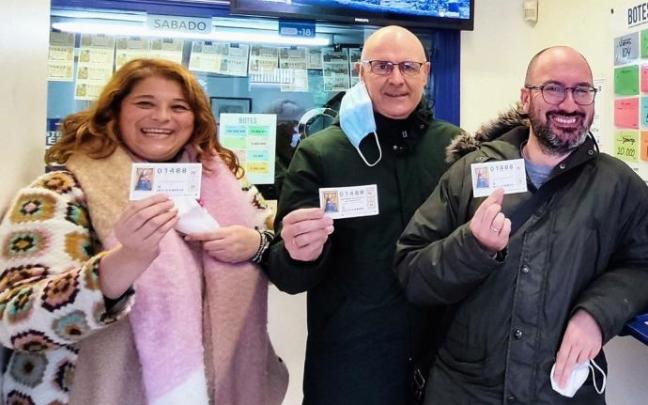 Tres personas muestran varios décimos de Lotería de Navidad.