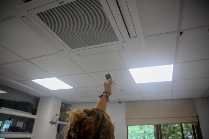 Una mujer enciende el aire acondicionado en una oficina.