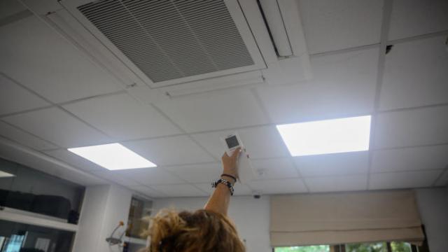 Una mujer enciende el aire acondicionado en una oficina.