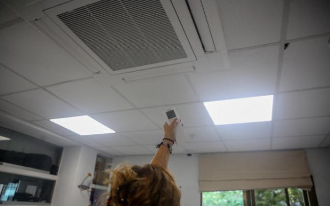 Una mujer enciende el aire acondicionado en una oficina. Una mujer enciende el aire acondicionado en una oficina.