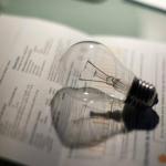 Una bombilla junto a la factura de la luz.