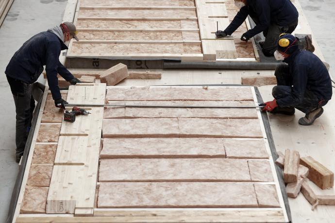 Varios trabajadores de la empresa Madergia terminan de elaborar una pared de madera para su uso en un futuro edificio