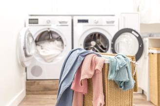 Cesto de la ropa sucia junto a una lavadora y una secadora.