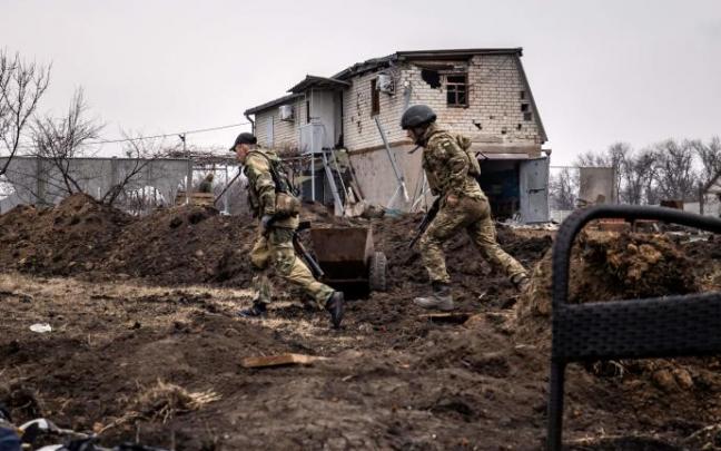 Soldados ucranianos frente a un edificio destruido.