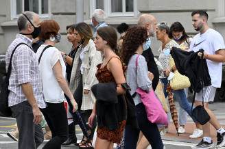 Varias personas con y sin mascarilla pasean por la calle