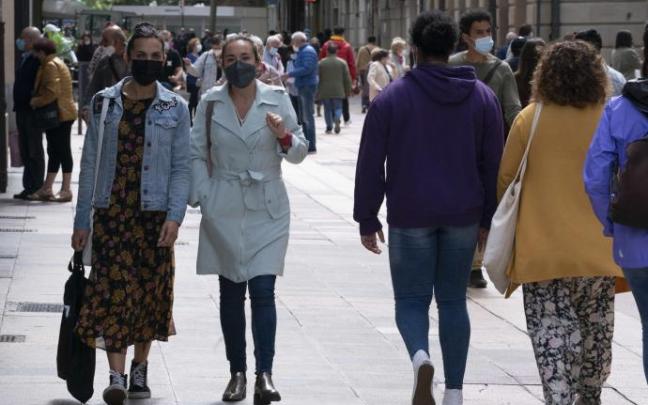 Personas andando por la calle con mascarilla.