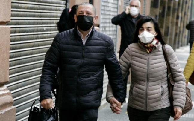 Dos personas pasean con la mascarilla puesta.