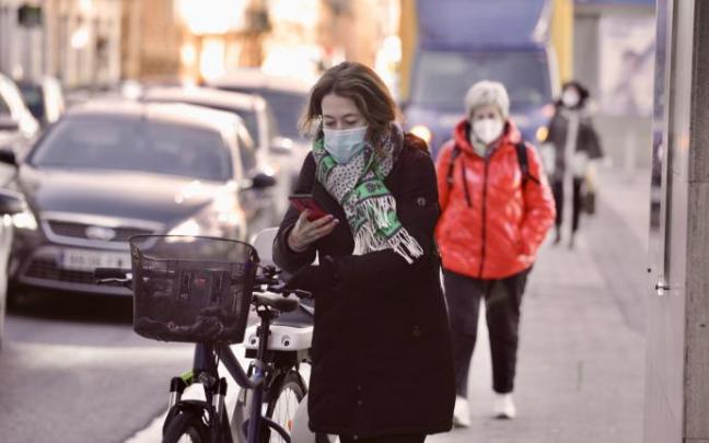Personas andando por la calle con mascarilla.