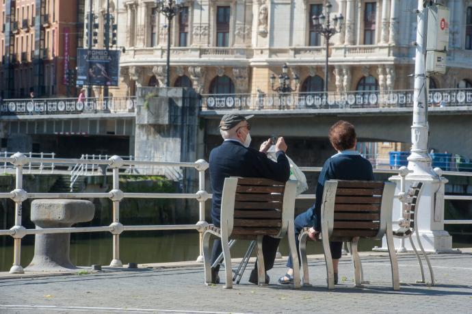 Una pareja sentada en un paseo de Bilbao junto a la ría