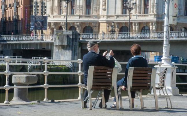 Una pareja sentada en un paseo de Bilbao junto a la ría Una pareja sentada en un paseo de Bilbao junto a la ría