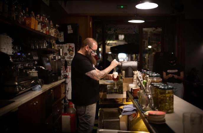 Un camarero trabajando en el interior de un bar con mascarilla.