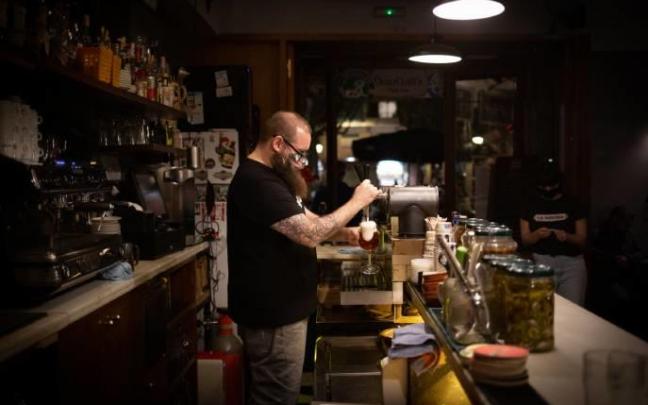 Un camarero trabajando en el interior de un bar con mascarilla.