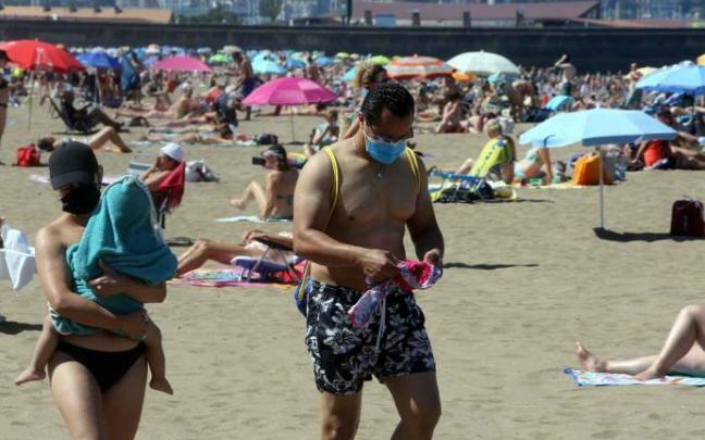 Dos bañistas con sus mascarillas en la playa Dos bañistas con sus mascarillas en la playa