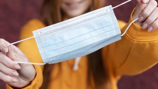 Una mujer sosteniendo una mascarilla.