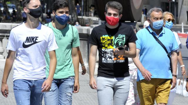 Un grupo de personas paseando por la calle con mascarilla. Un grupo de personas paseando por la calle con mascarilla.
