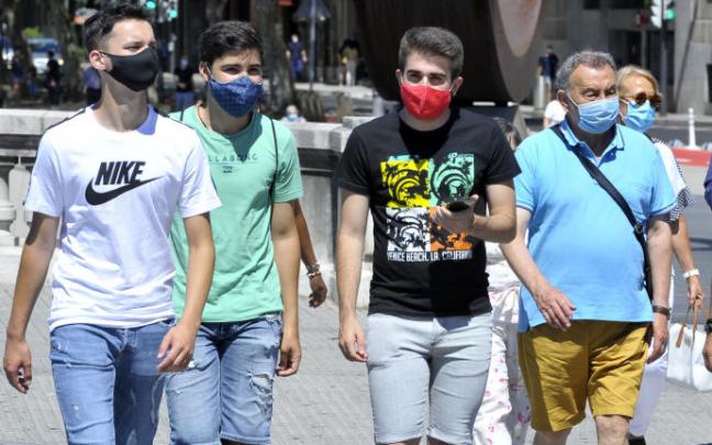 Un grupo de personas paseando por la calle con mascarilla.