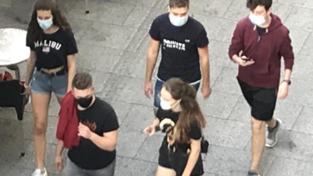 Varios jóvenes pasean con la mascarilla puesta.