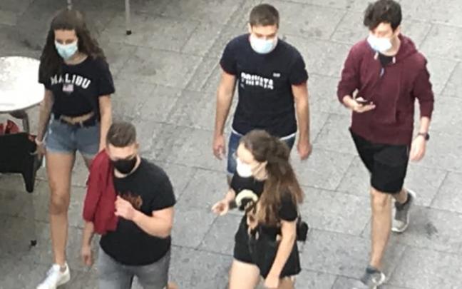 Varios jóvenes pasean con la mascarilla puesta.