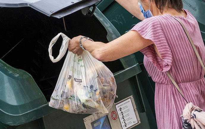 Una mujer tirando la basura en un contenedor