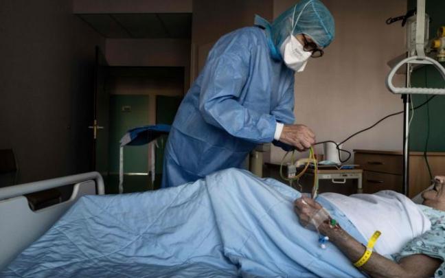 Un sanitario atiende a un paciente con covid en una UCI Un sanitario atiende a un paciente con covid en una UCI