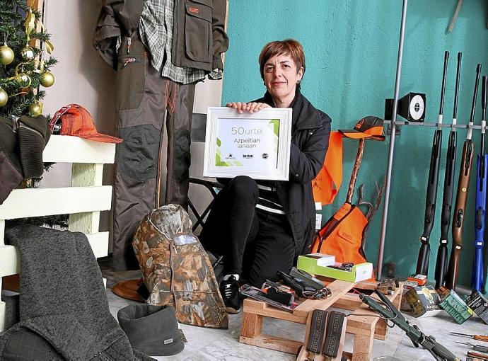 Gaizkane Larrañaga posa con la placa entregada por el Ayuntamiento en el interior de su tienda.