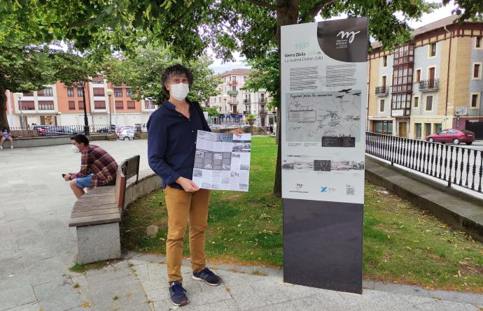 Iosu Gallarreta sostiene el plano con el itinerario al lado de un punto informativo situado en la plaza Euskadi.