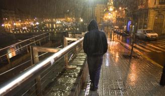 Una persona camina por la calle en una noche lluviosa.