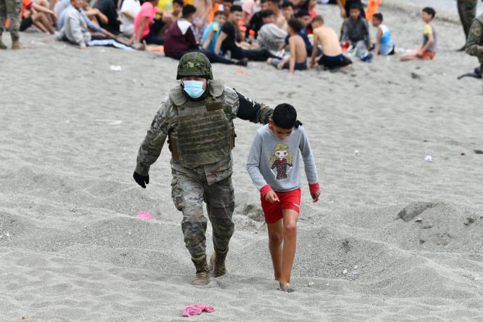 Un militar acompaña a uno de los menores llegados a Ceuta.