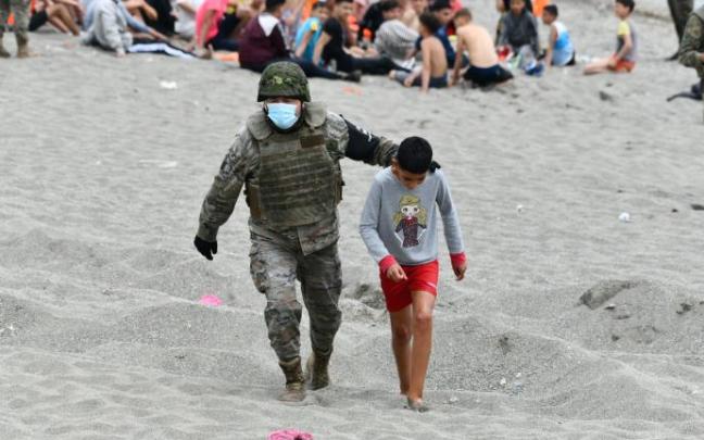 Un militar acompaña a uno de los menores llegados a Ceuta.
