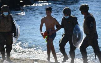 Un militar ayuda a un menor migrante procedente de Marruecos a su llegada a Ceuta