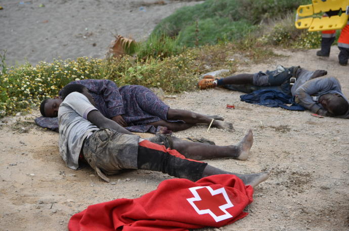 Un grupo de migrantes tumbados en la playa tras cruzar a nado hasta Ceuta
