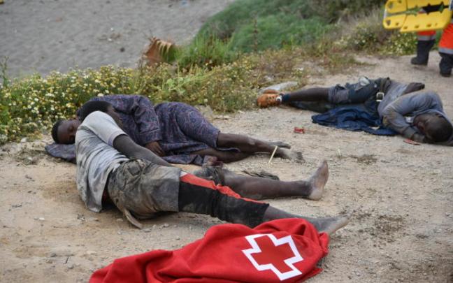 Un grupo de migrantes tumbados en la playa tras cruzar a nado hasta Ceuta