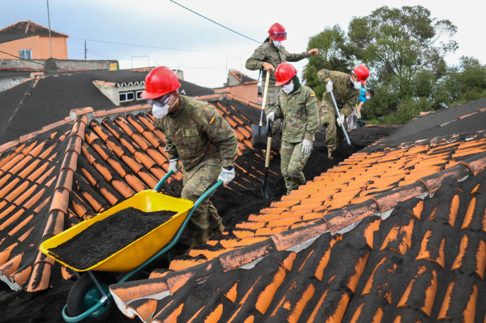 Militares retiran ceniza de un tejado.