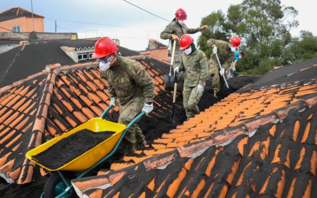 Militares retiran ceniza de un tejado.